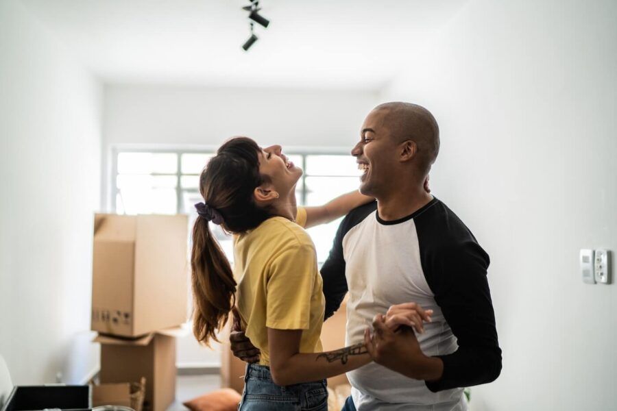 Happy young couple dancing in the new living room surrounded by moving boxes