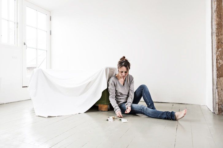 Mature woman sitting on floor in empty house, counting money