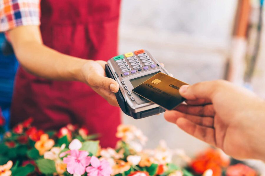 A customer taps their credit card on a credit card reader from a flower shop owner.