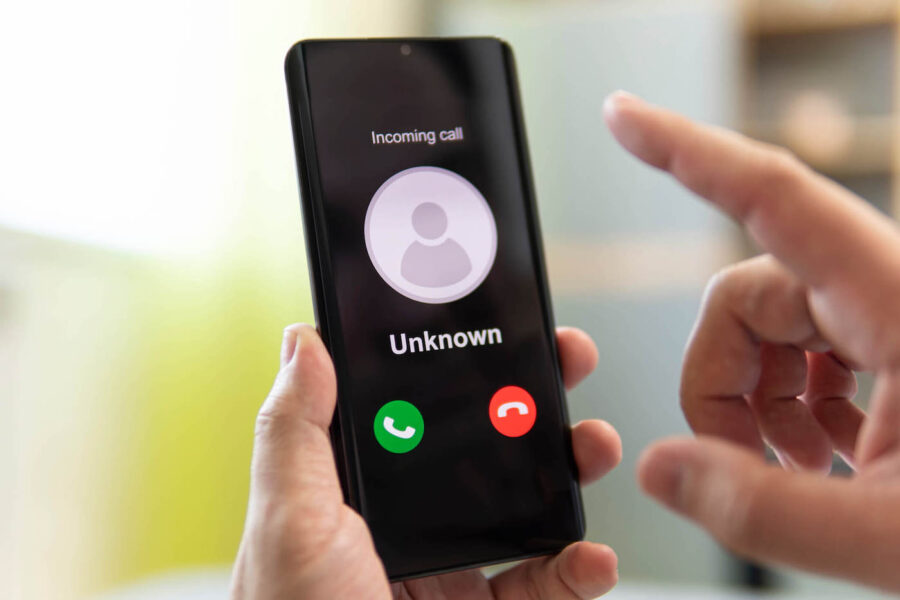 A person holds a phone that displays an incoming call from an unknown caller.