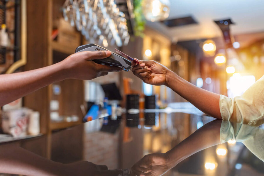A person taps their credit card on a card reader to pay at the bar.