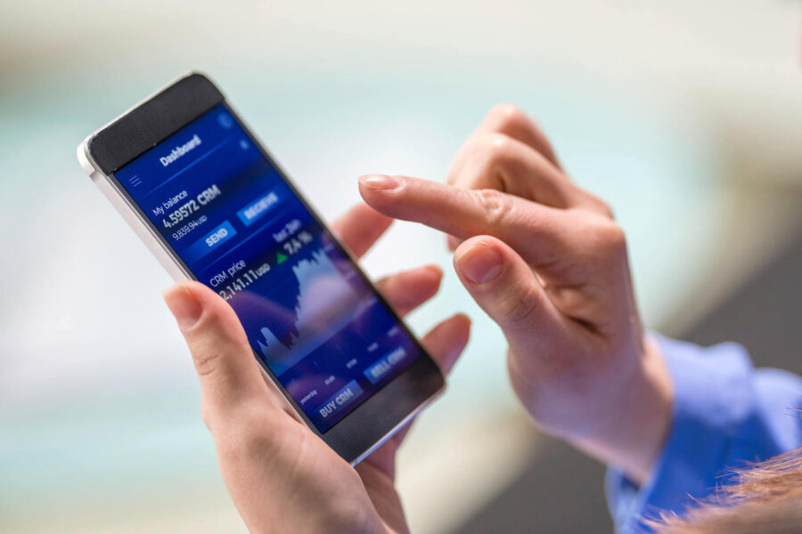 A person holds a phone that is showing a blue investment chart on the screen.