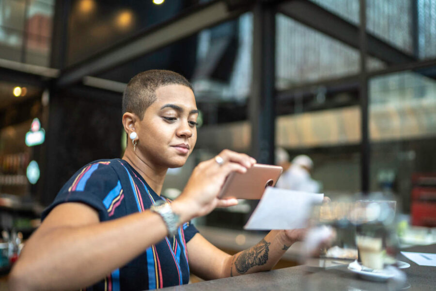 A woman takes a picture of a check while inside a restaurant.