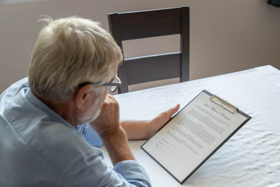 An elderly man looks over his last will and testament document.