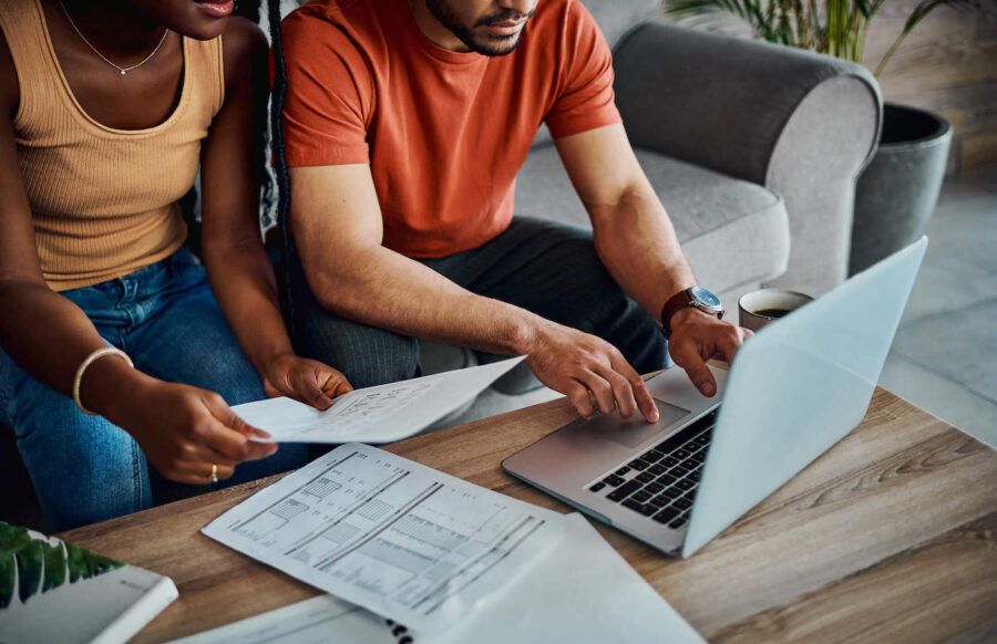Cropped shot of an unrecognisable couple sitting in the living room and using a laptop to calculate their finances.