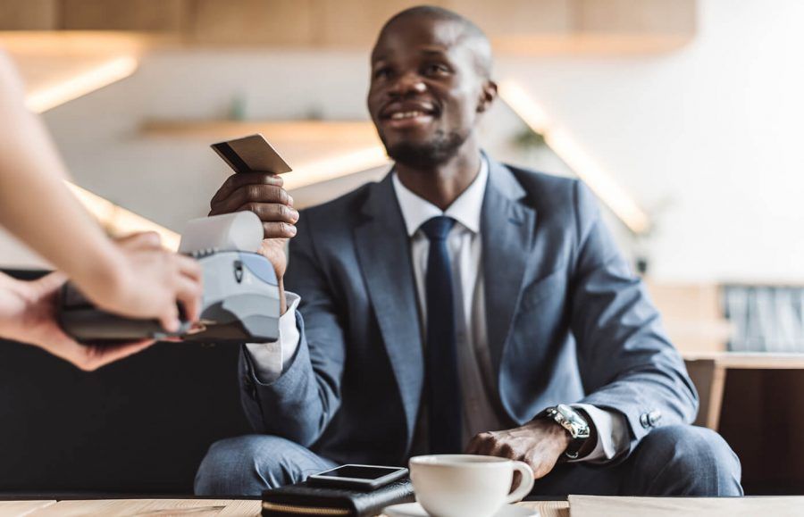 A man in a suit paying for a coffee with his card.