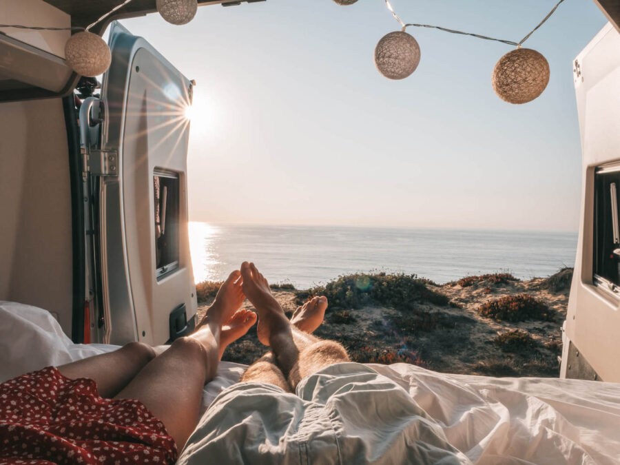 couple lying down in an open rv by the beach