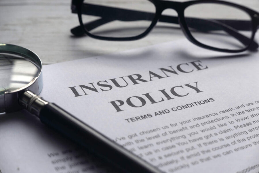 insurance policy paper next to magnifying glass and glasses