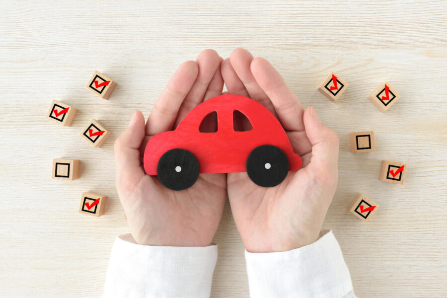 hands holding a red car model offering guidance to cancel car insurance