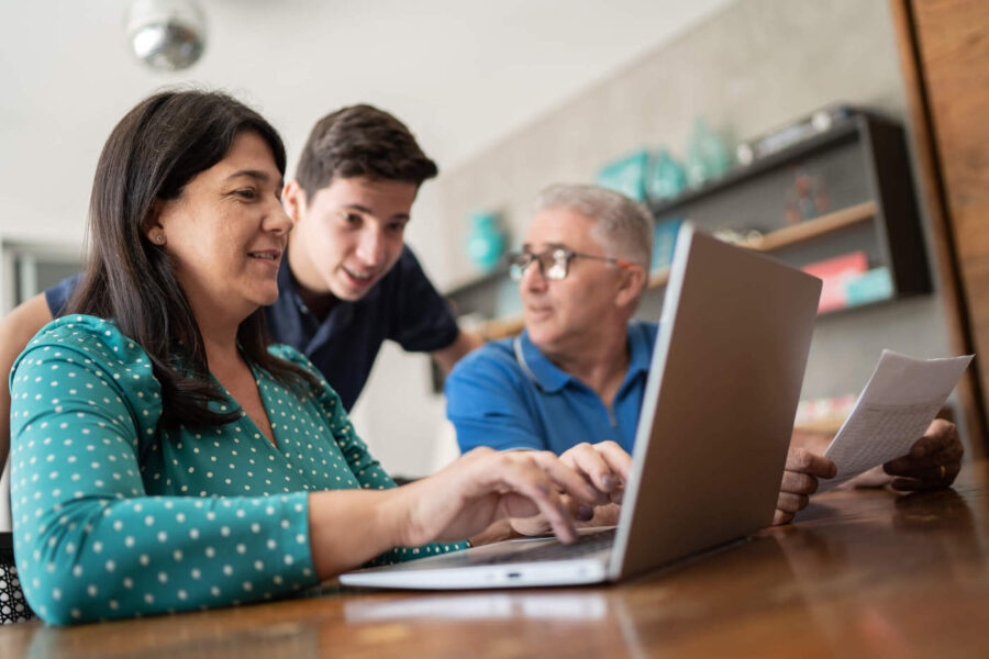 family of three sitting around table comparing mortgage loan offers on laptop