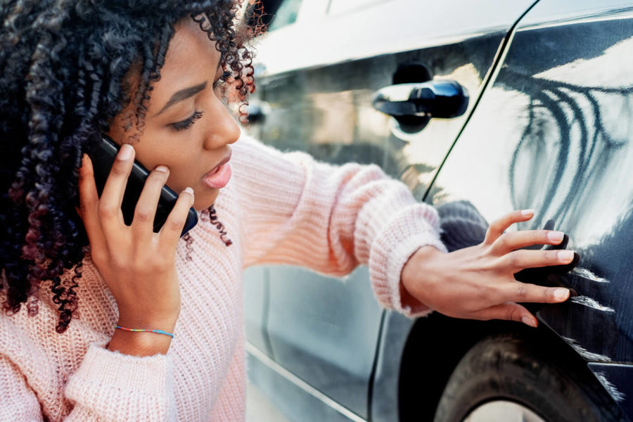 Black woman feeling sad after scratching her auto