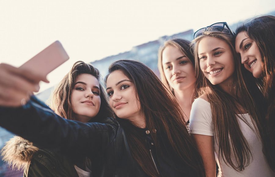 group of five young woman taking a selfie