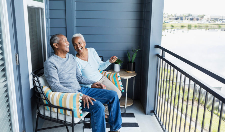 Senior couple relaxing on porch, holding hand, laughing
