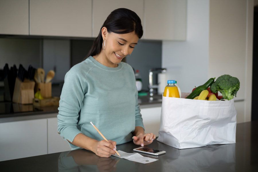 Woman at home checking the receipt after grocery shopping