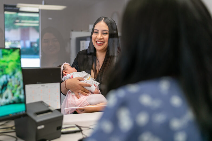Mother holding her baby at a bank window planning for the baby's college fund