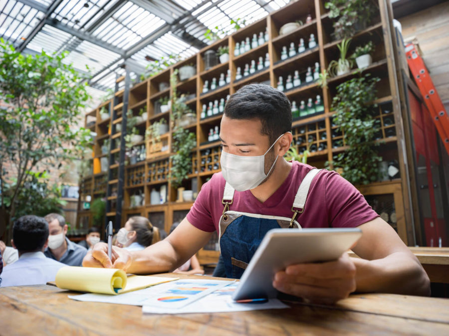 Business manager doing the books at a restaurant wearing a facemask