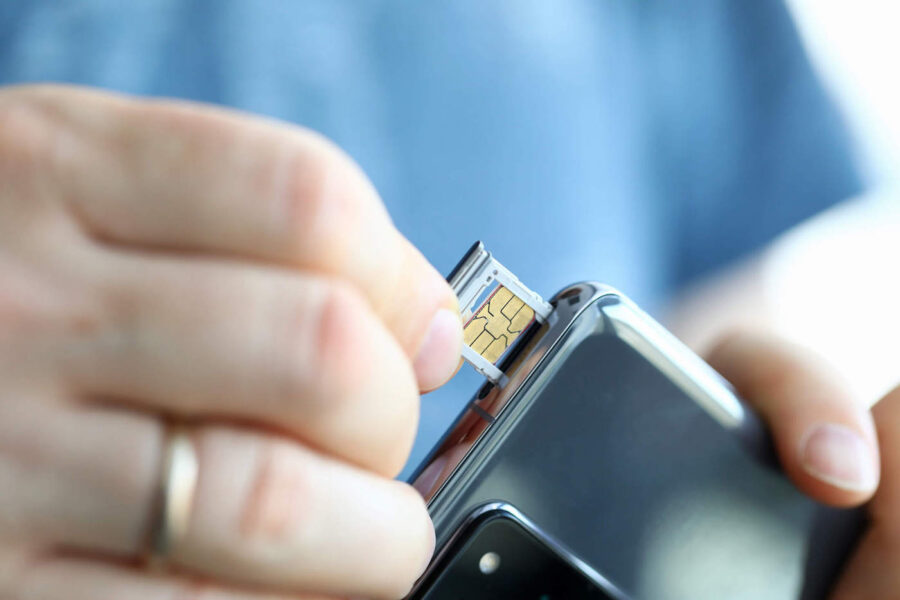A person wearing a blue shirt puts their SIM card into their phone.