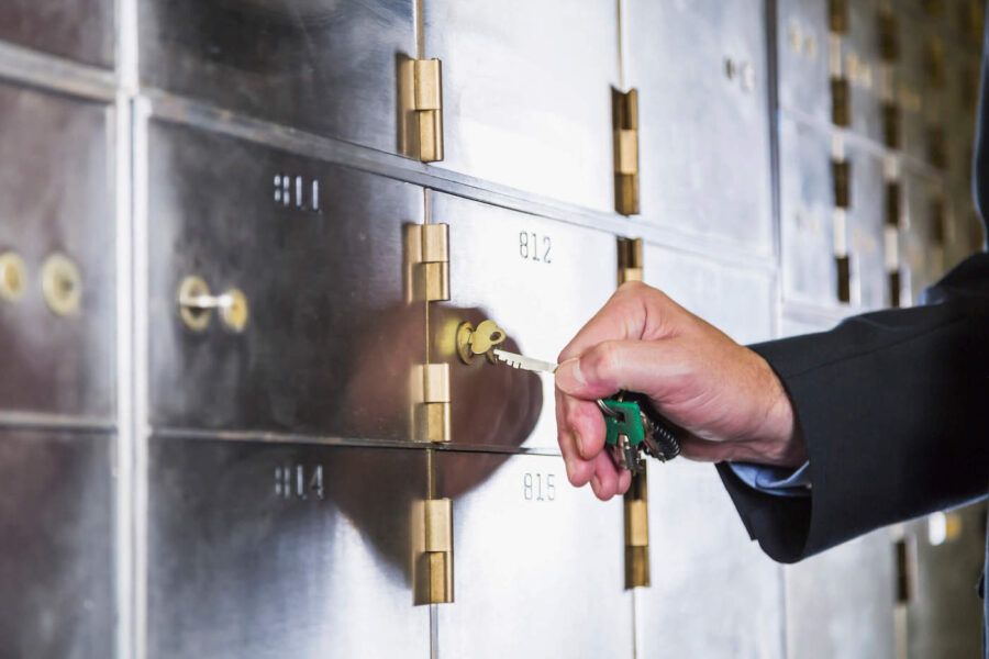 A person uses a key to open their safety deposit box.