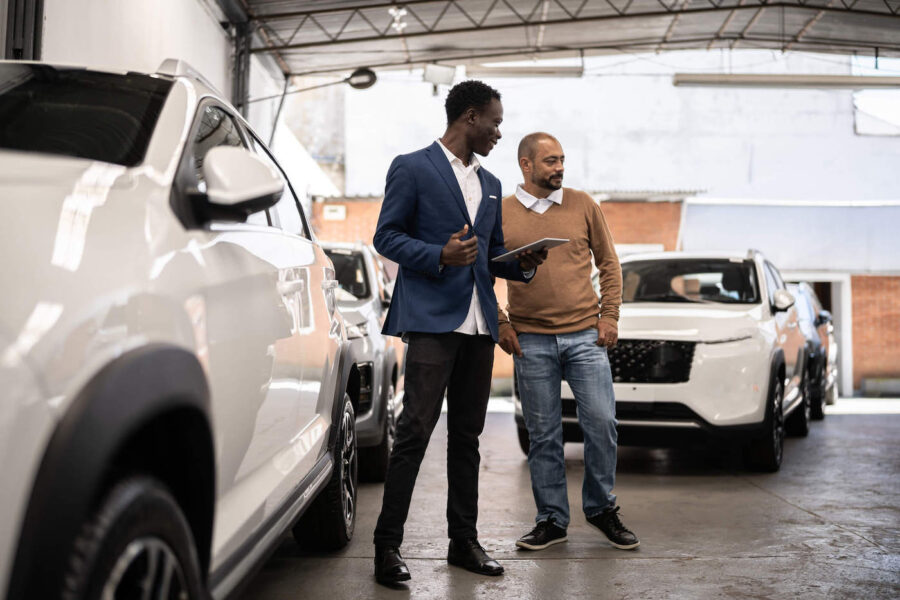 Salesman showing car to customer in a car dealership.