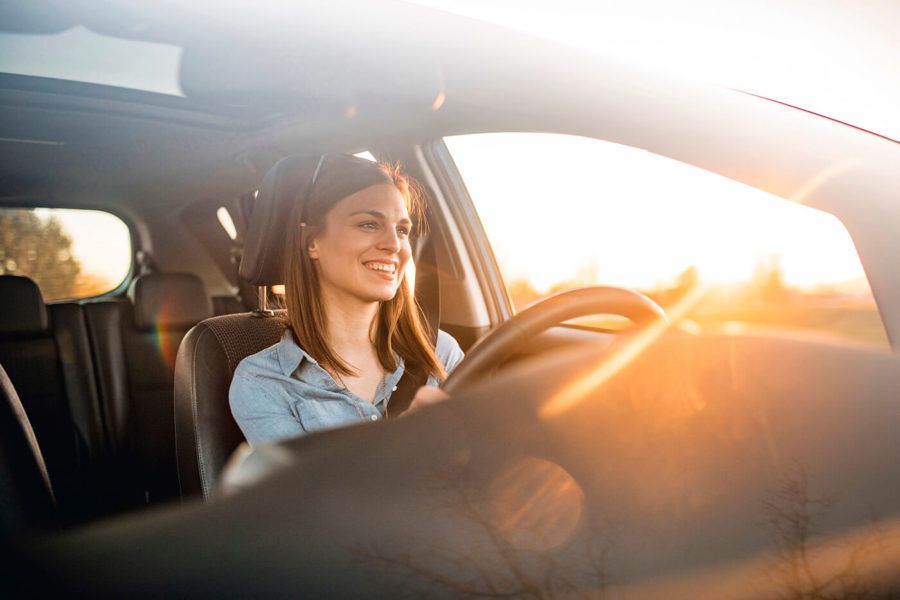 Young woman smiling and driving her car on a sunny day
