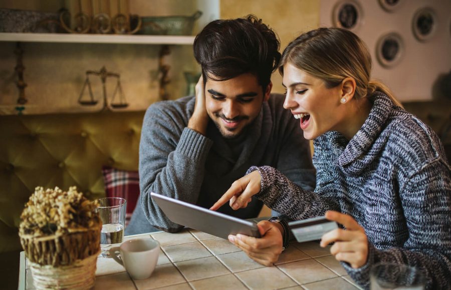 Laughing and smiling couple looking at tablet and holding credit card