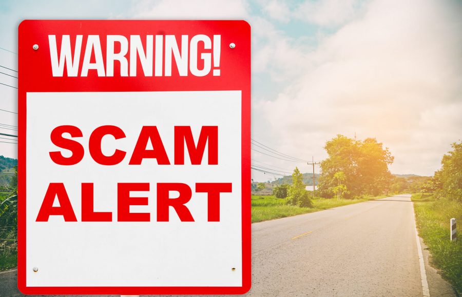 red and white sign warning of scam alert