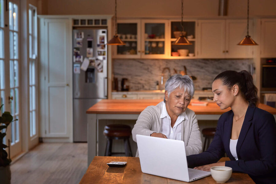 two women sitting on table looking at return of premium life insurance on laptop