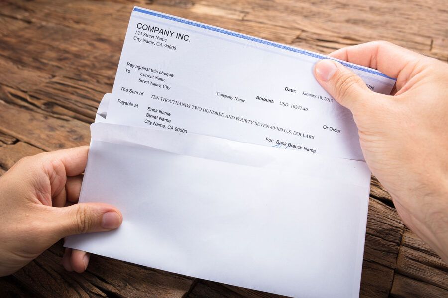 A person opens up an envelope containing a check from a company.