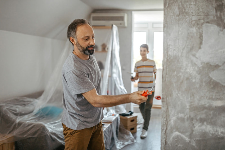 Father and son repainting wall apartment