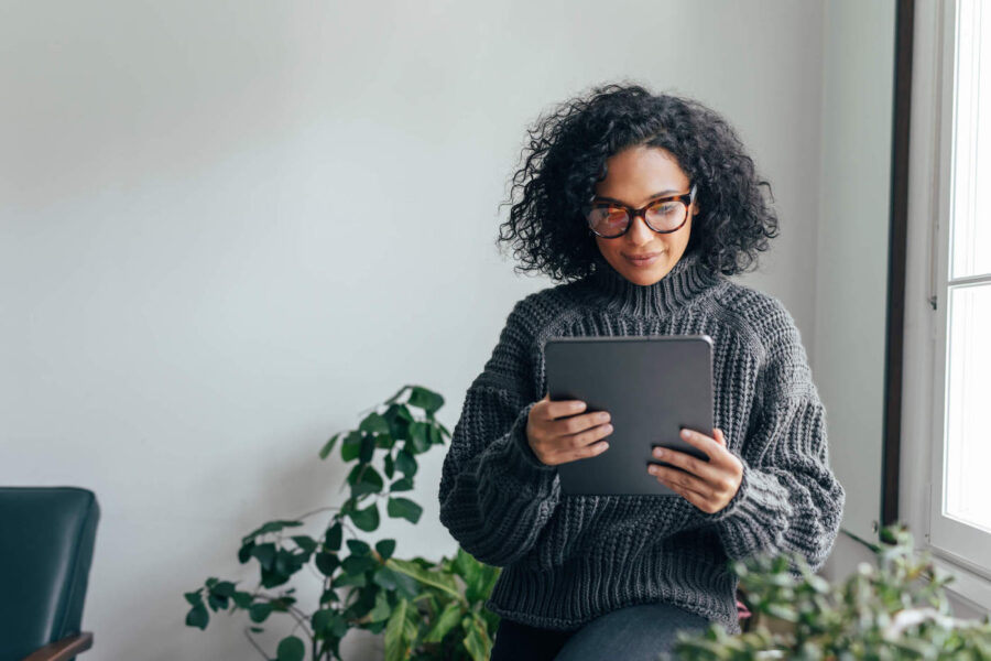 woman in grey oversized turtleneck holding a tablet researching nonqualified retirement plans