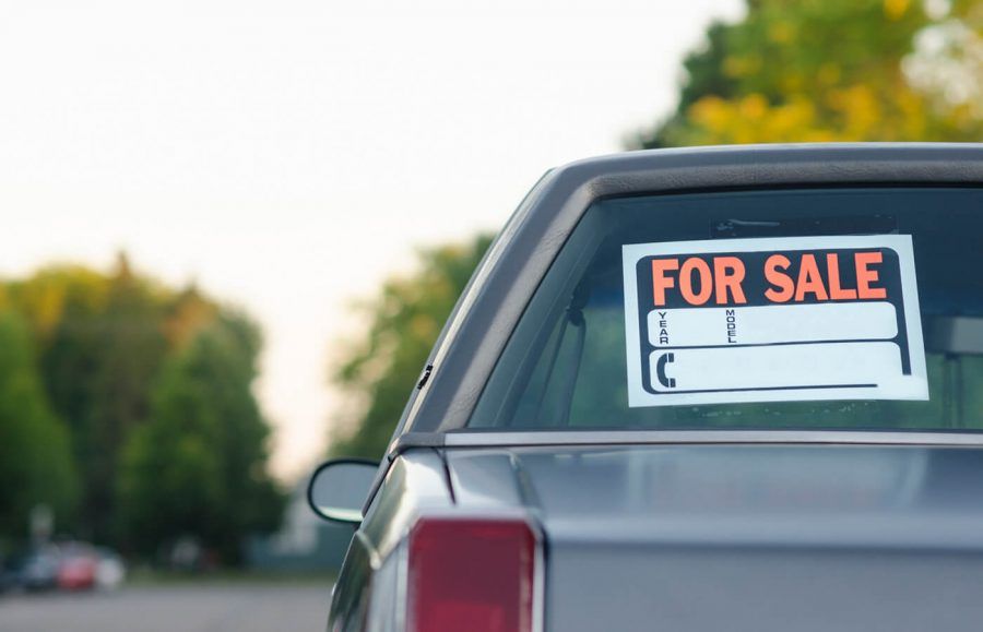 A car with a For Sale sign posted in the back windshield.