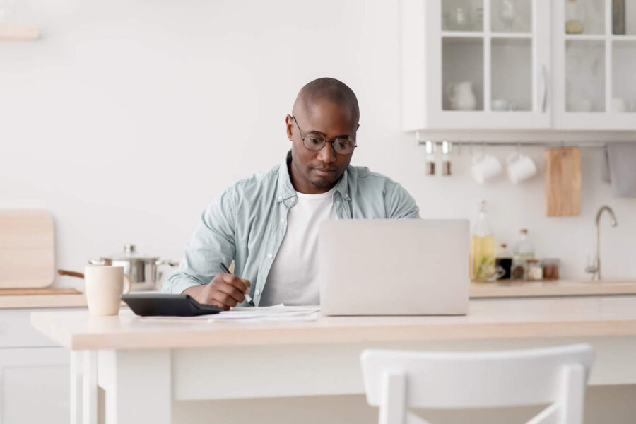 man sitting on kitchen counter researching HELOCs on laptop
