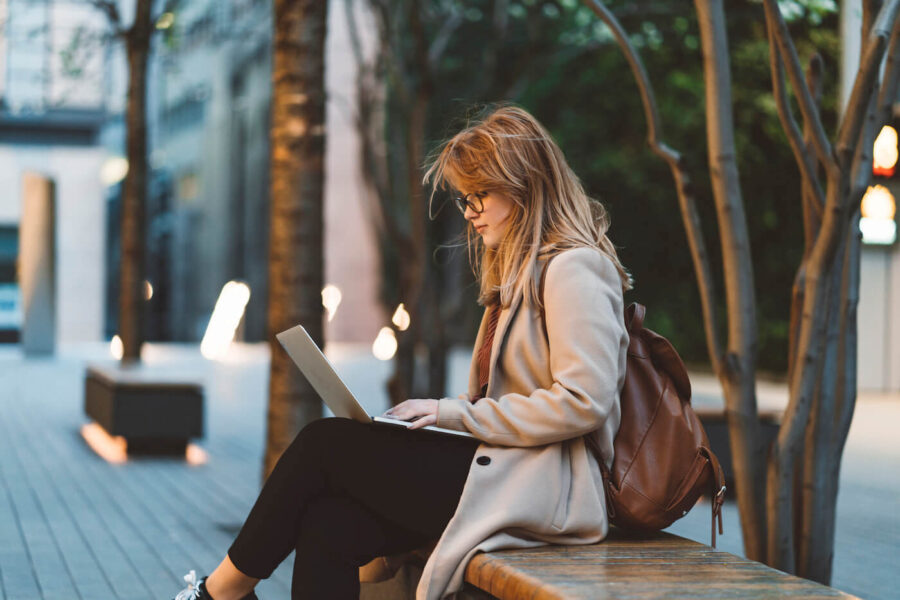 Woman using laptop on a bench.