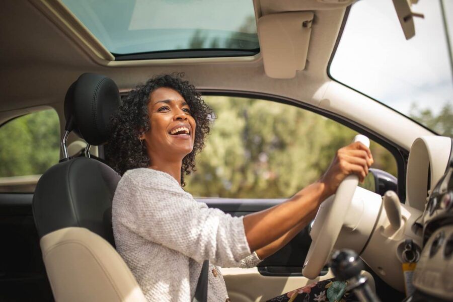 Smiling woman looking into the rearview mirror while driving a car