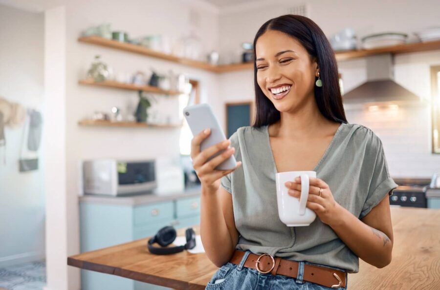 Smiling woman with a mug is using her mobile banking app