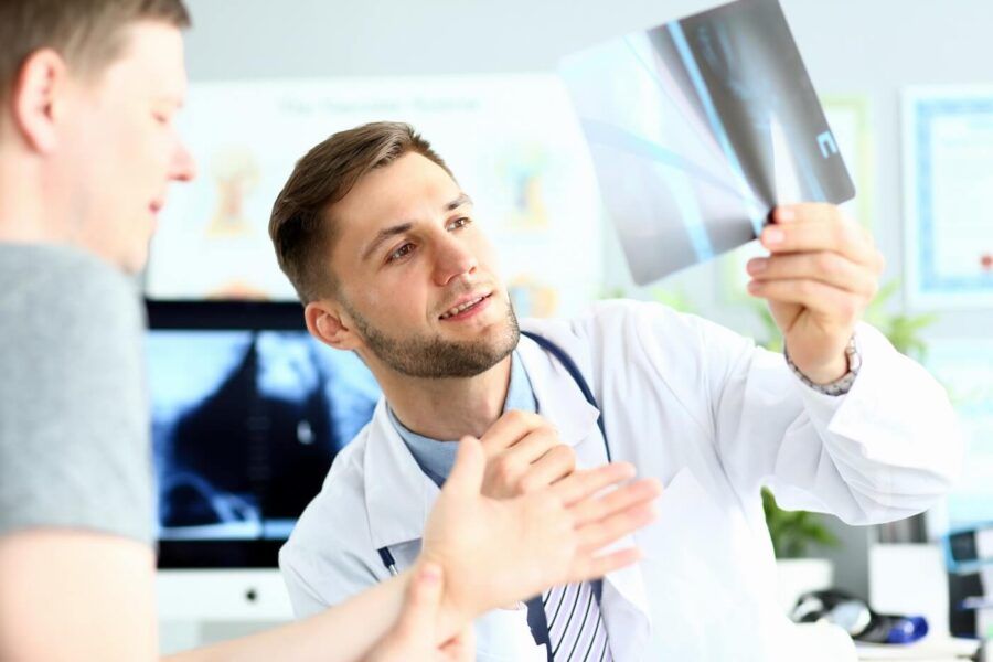 Doctor is looking at the male patient's X-ray