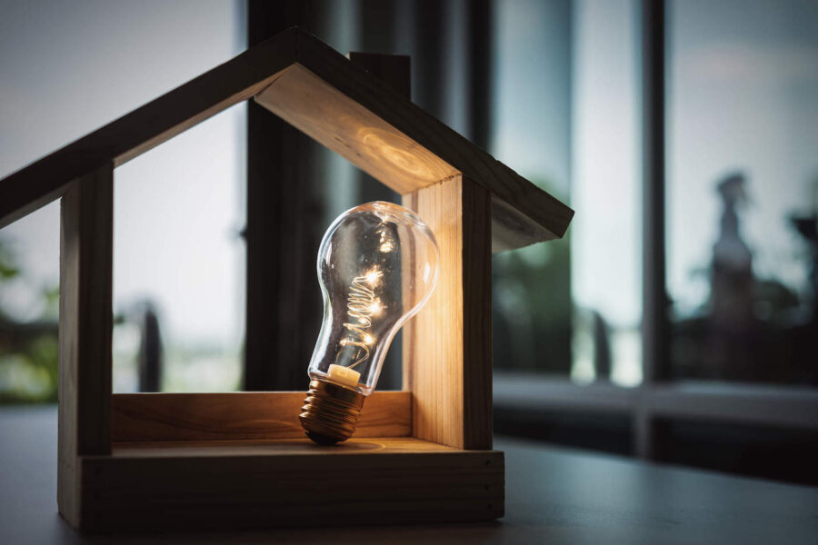 Bright lightbulb inside wooden house model frame.