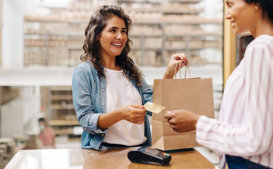 Smiling young woman paying with a credit card at a department store checkout counter
