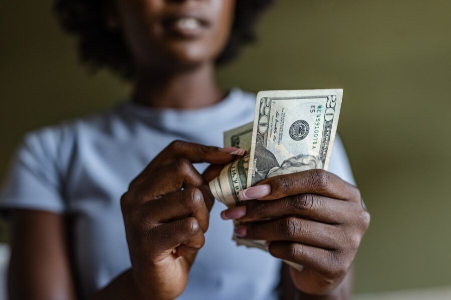 A woman holding and counting dollars.