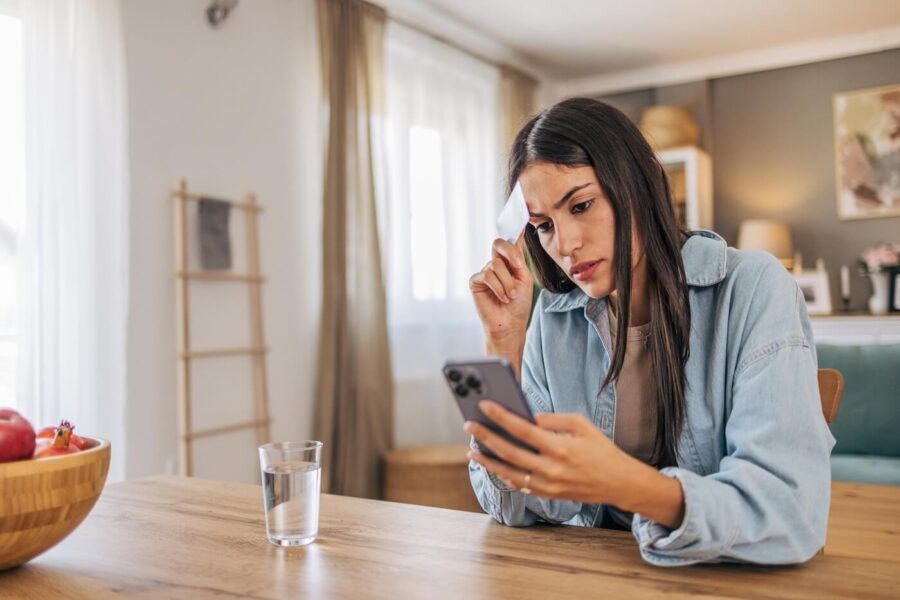 Concerned young woman holding a credit card while checking her bank account on the smartphone