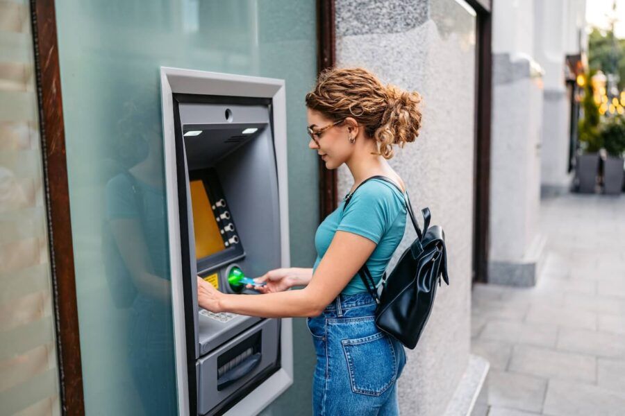 Young woman withdrawing cash from an ATM outdoors