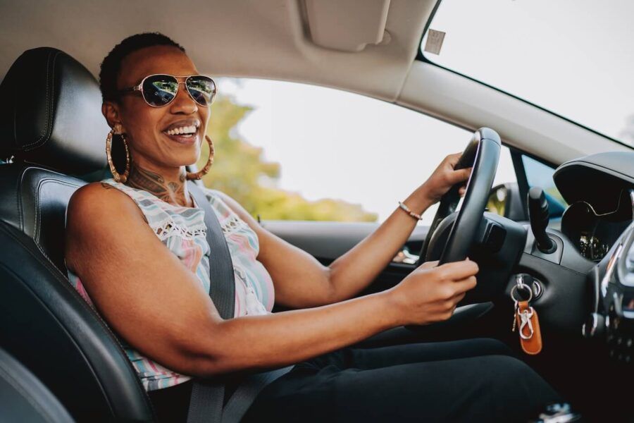 Smiling mature woman in sunglasses driving a car