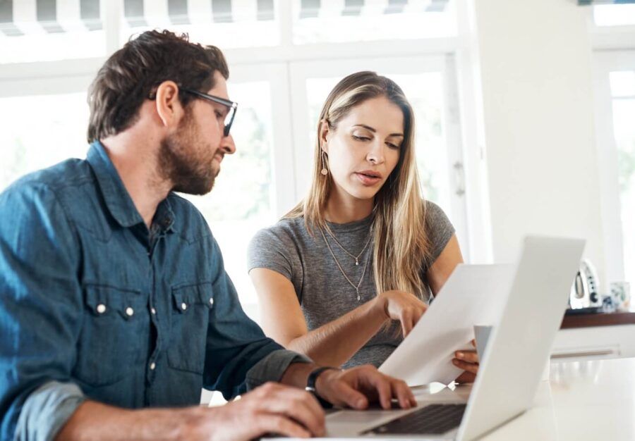 Focused couple discussing their finances at home while using the laptop