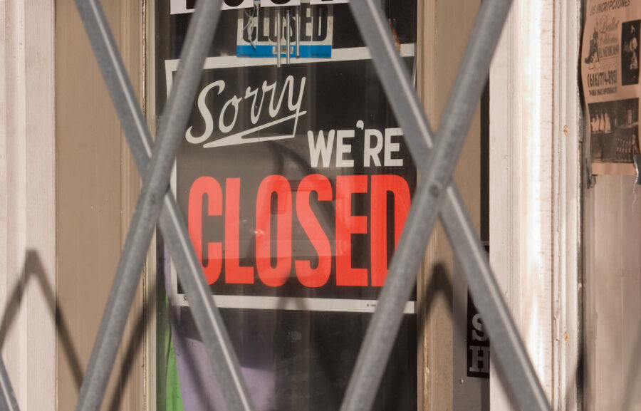 Closed sign on glass door behind metal gate