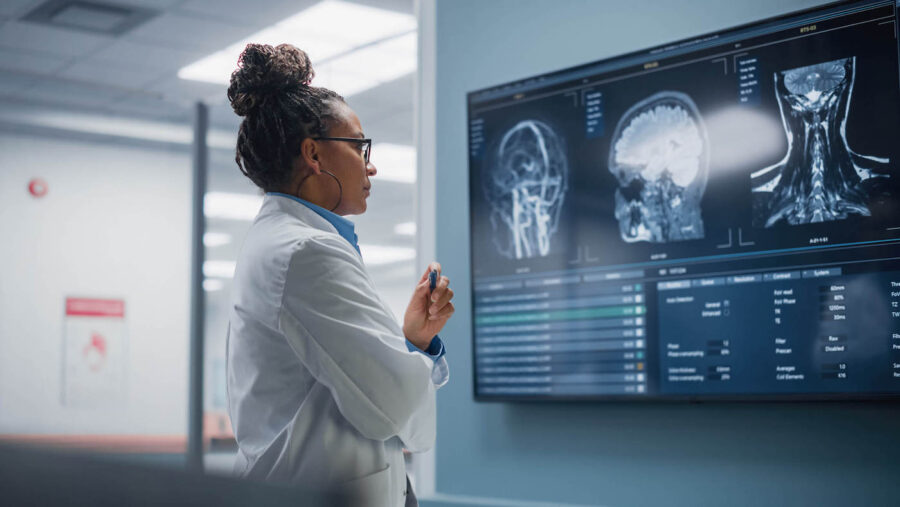 Confident black female doctor looking at a screen of medical data.