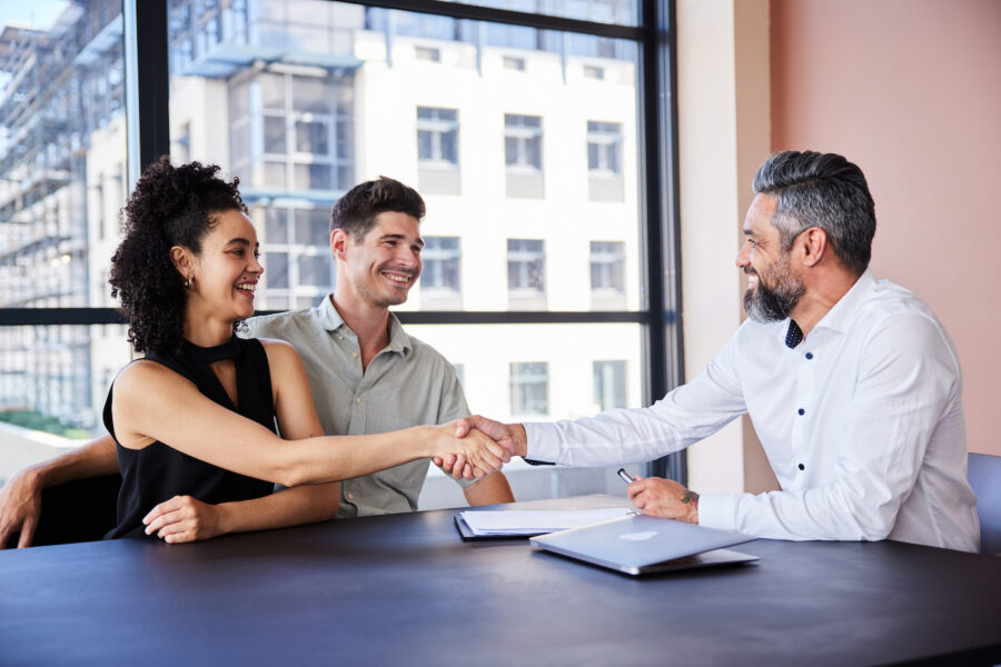 Couple shaking hands with a banker after discussing home equity