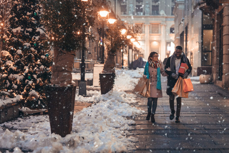 Young couple enjoy shopping for holiday gifts in the snow.