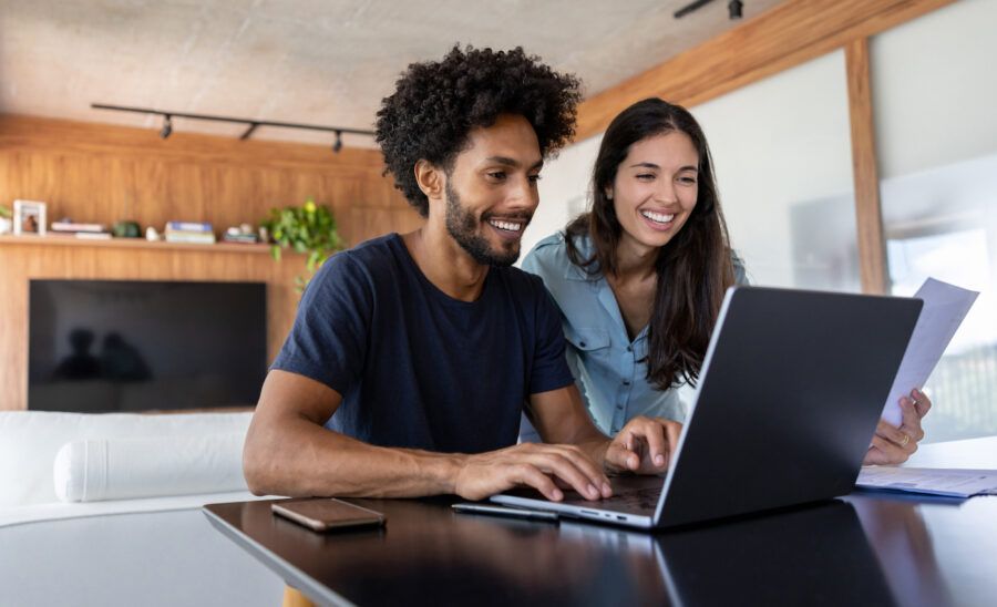 Young couple at home looking over mortgage online on a laptop computer.