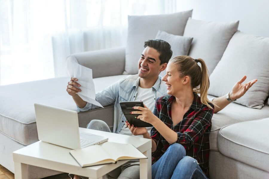 Photo of a happy couple doing finances at home, effectively managing their savings account.