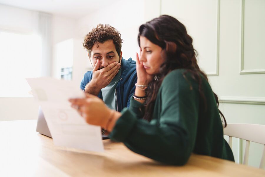 A couple looking at their bills, realizing the mistakes they've made in handling their debt.